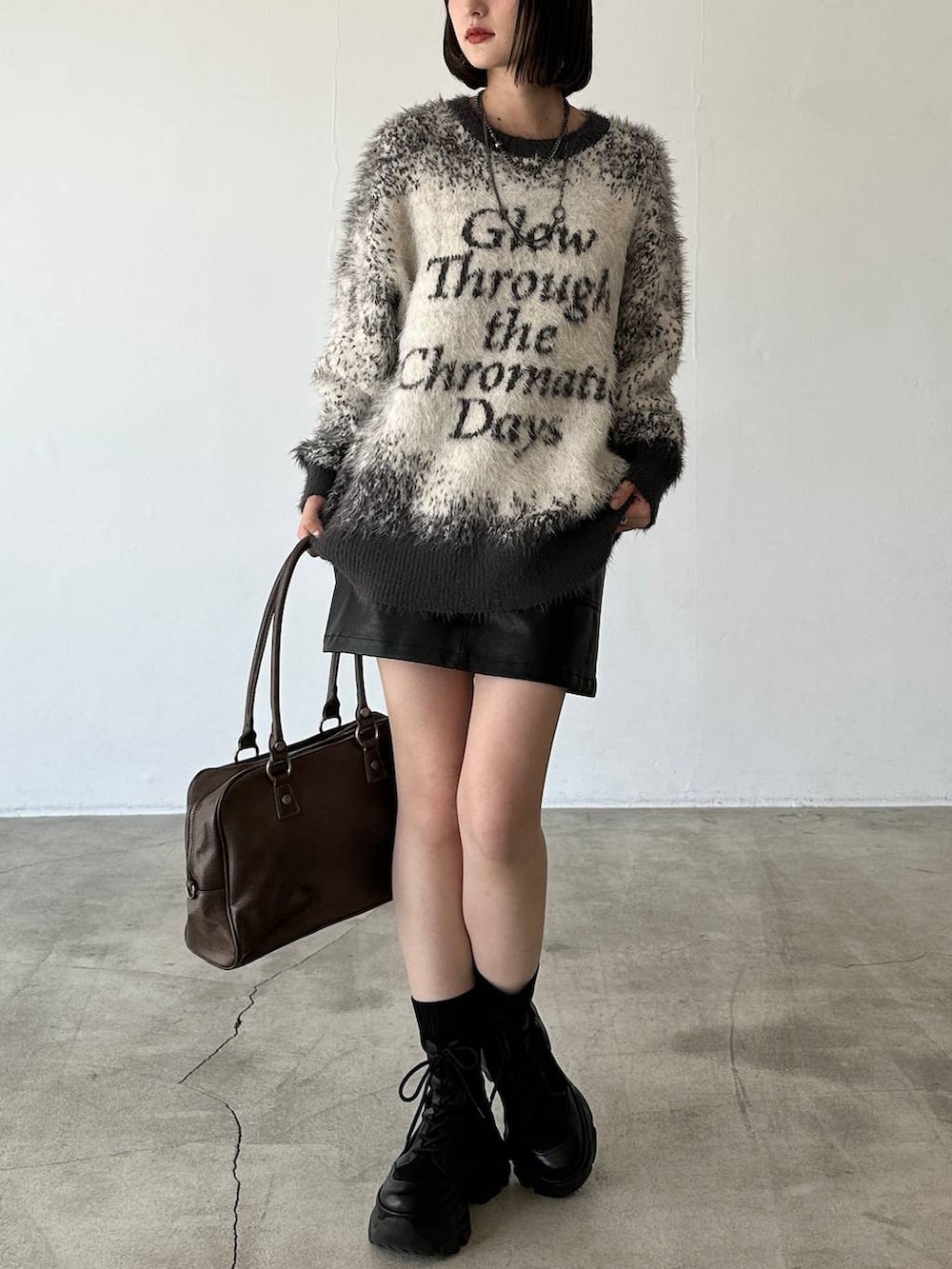 ブラック系のブーツ、ブラウン系のボストンバッグ、グレー系のニット/セーターを着用したレディースの秋コーディネートの3枚目の写真