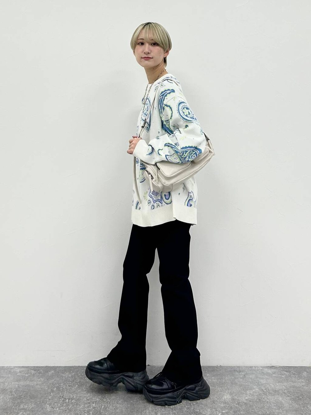 ブラック系のスニーカー、ホワイト系のショルダーバッグ、ブラック系のデニムパンツを着用したレディースの冬コーディネートの3枚目の写真