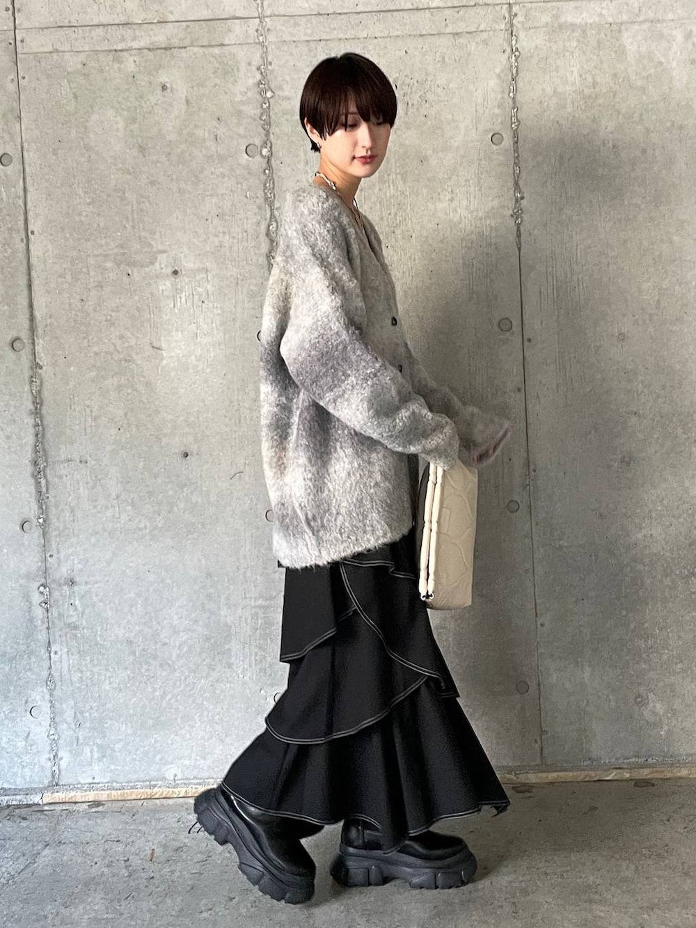 ホワイト系のキャミソール、ブラック系のブーツ、ホワイト系のクラッチバッグを着用したレディースの冬コーディネートの6枚目の写真