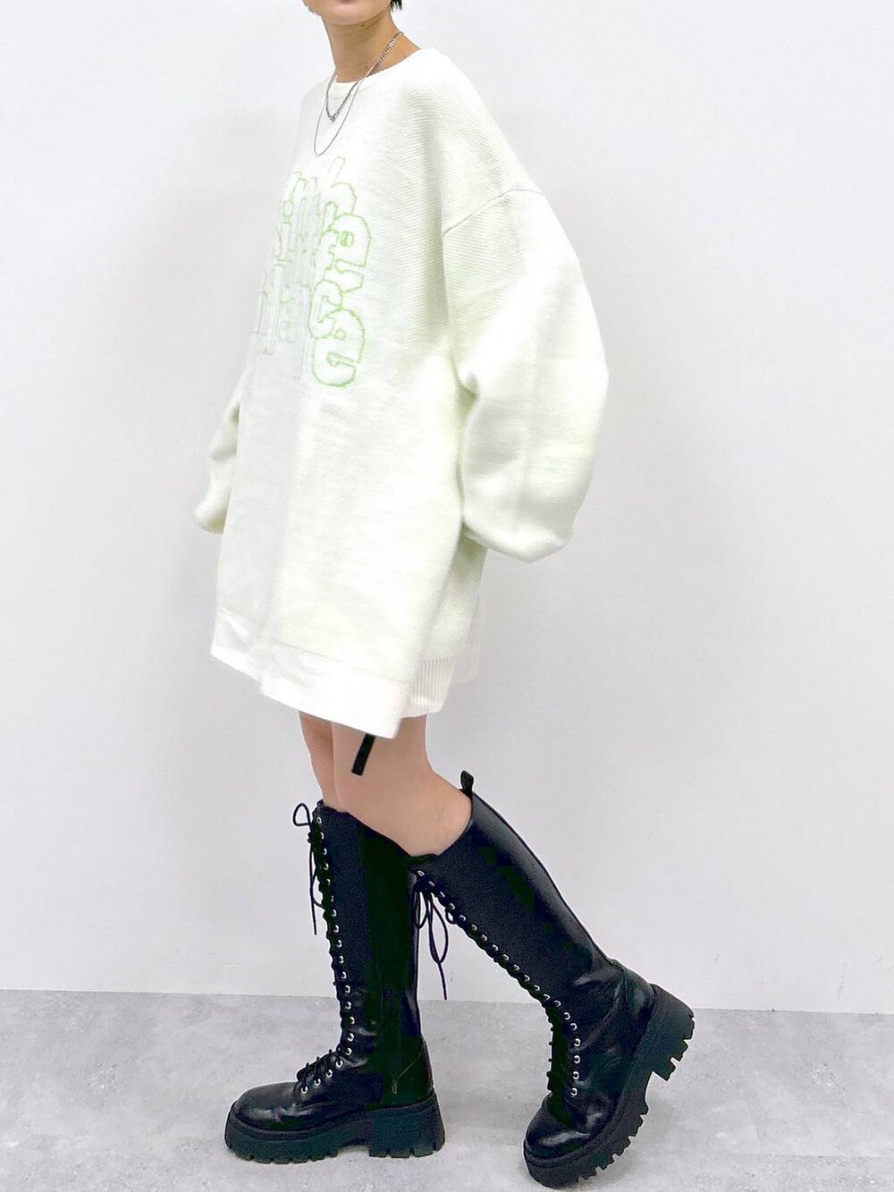 ブラック系のブーツ、ブラック系のスカート、ホワイト系のニット/セーターを着用したレディースの冬コーディネートの3枚目の写真