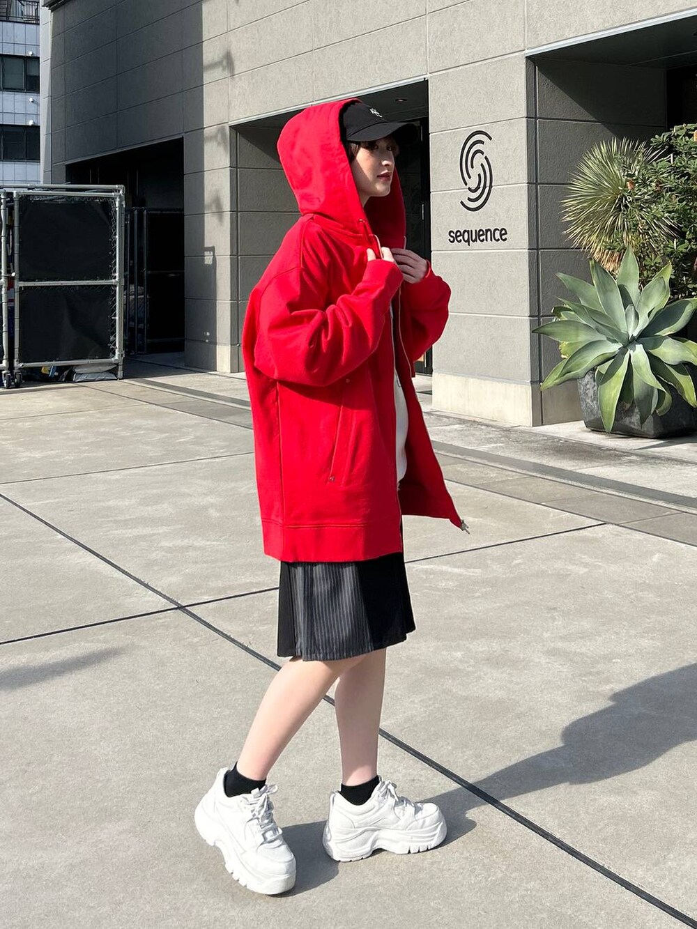 レッド系のパーカー、ホワイト系のニット/セーター、ブラック系のスラックスを着用したレディースの冬コーディネートの6枚目の写真