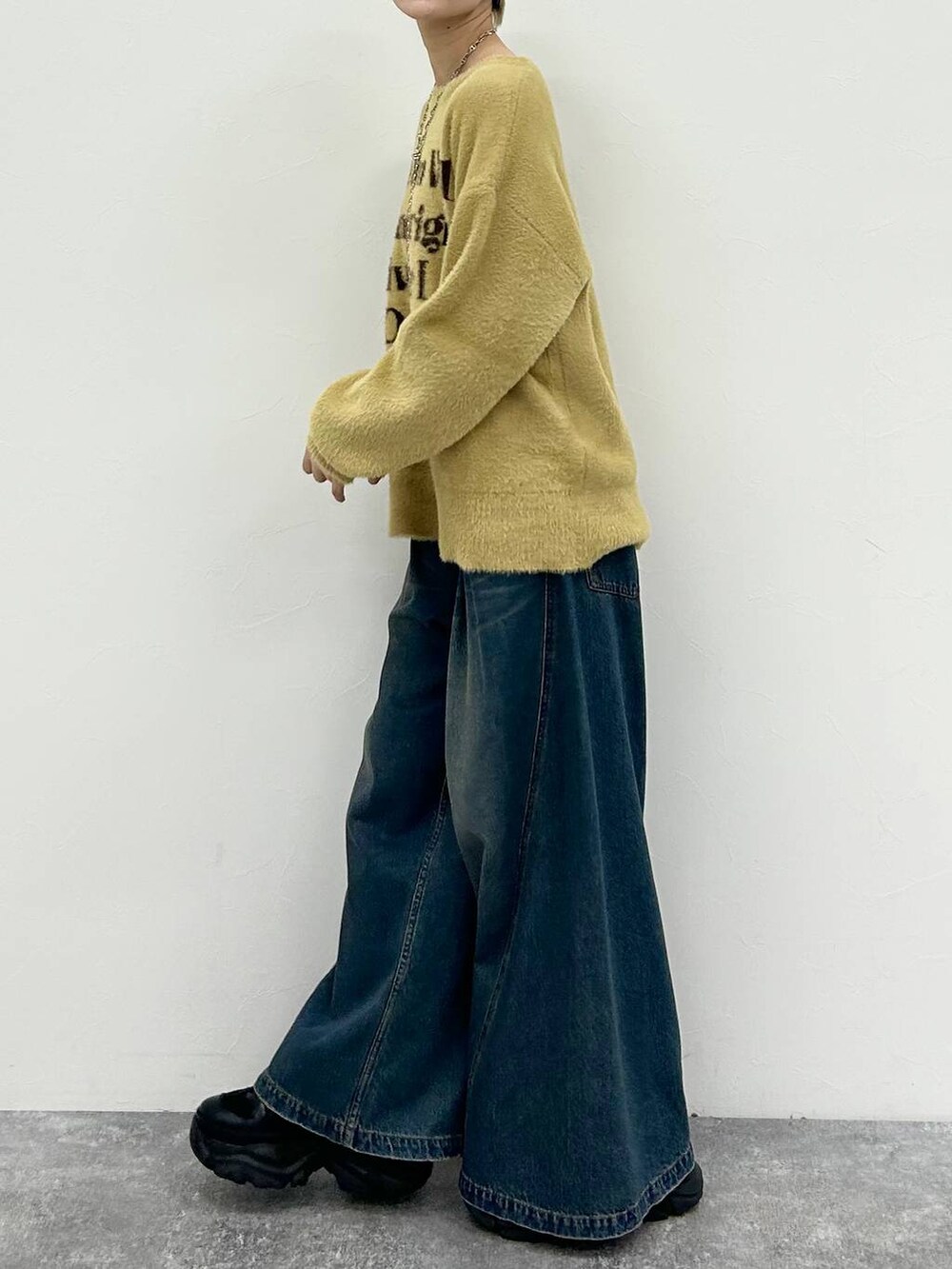 ブラック系のスニーカー、ブルー系のデニムパンツ、イエロー系のニット/セーターを着用したレディースの春コーディネートの5枚目の写真