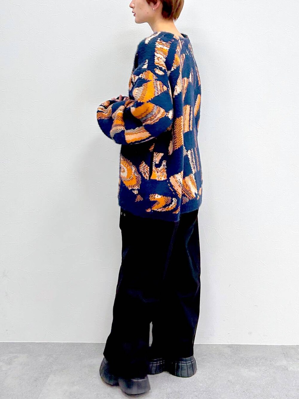 ブルー系のニット/セーター、ブラック系のブーツ、ブラック系のスラックスを着用したレディースの冬コーディネートの4枚目の写真