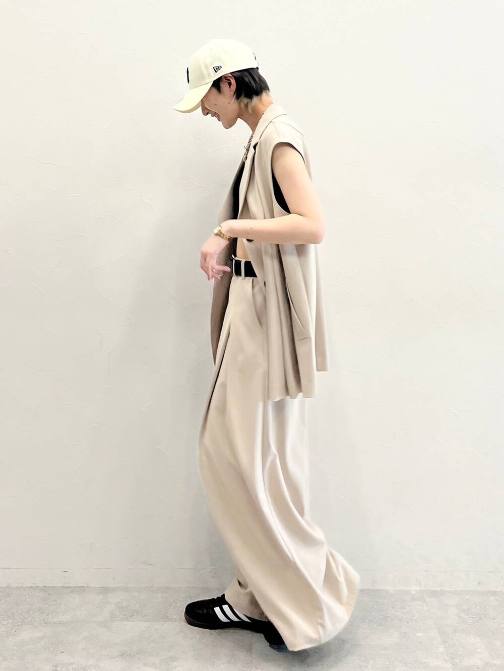 ブラック系のキャミソール、ベージュ系のスラックス、ブラック系のスニーカーを着用したレディースの春コーディネートの3枚目の写真