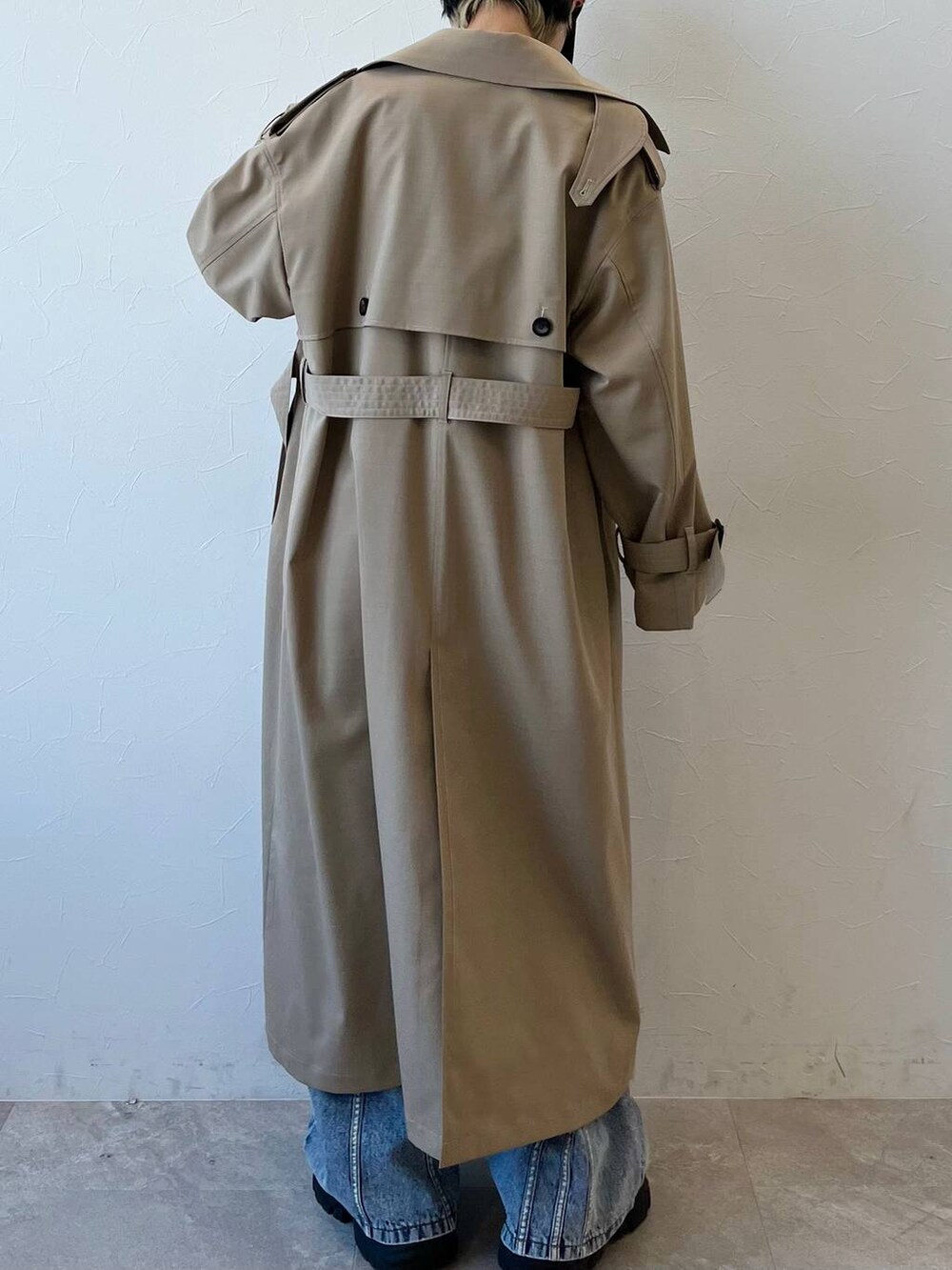 ブラック系のスニーカー、ベージュ系のトレンチコート、ブルー系のデニムパンツを着用したレディースの春コーディネートの7枚目の写真