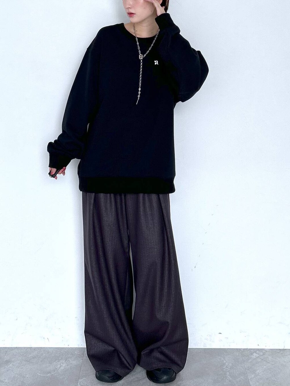 ブラウン系のスラックス、ブラック系のスウェット、シルバー系のピアス（両耳用）を着用したレディースの夏コーディネートの2枚目の写真