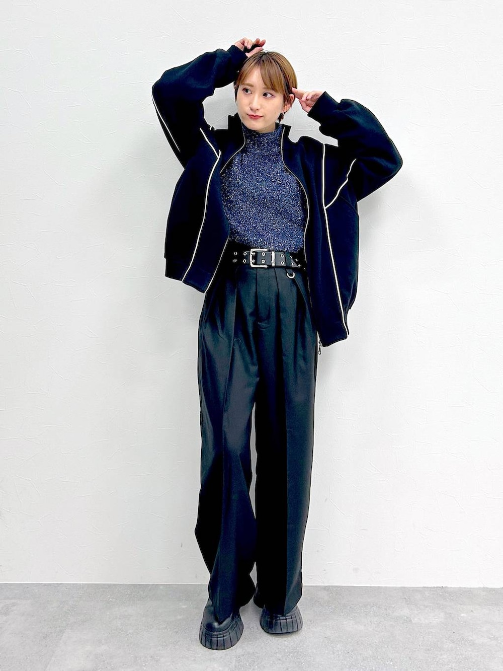 ブラック系のスウェット、ブラック系のブーツ、ブラック系のスラックスを着用したレディースの冬コーディネートの2枚目の写真