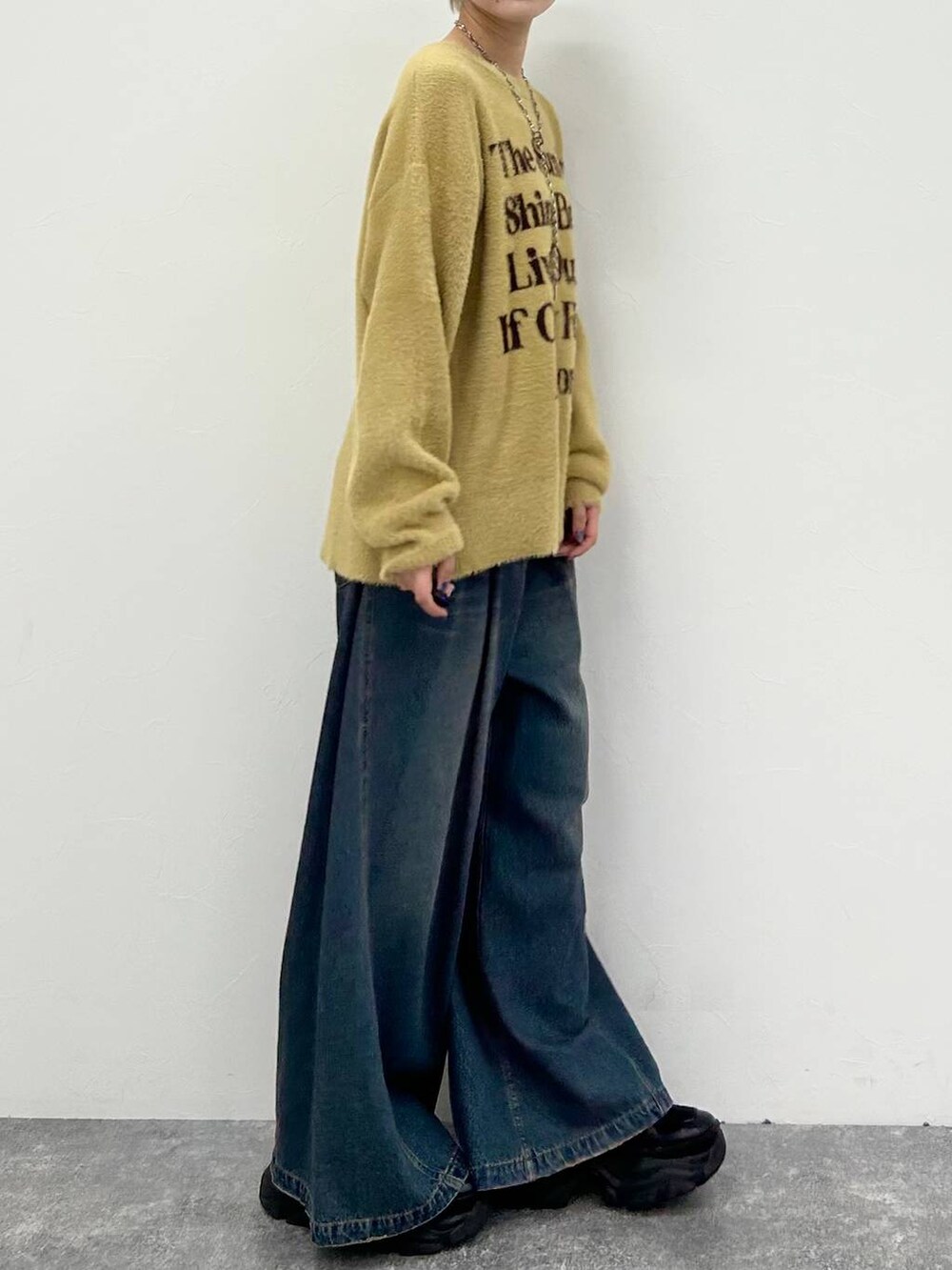 ブラック系のスニーカー、ブルー系のデニムパンツ、イエロー系のニット/セーターを着用したレディースの春コーディネートの7枚目の写真