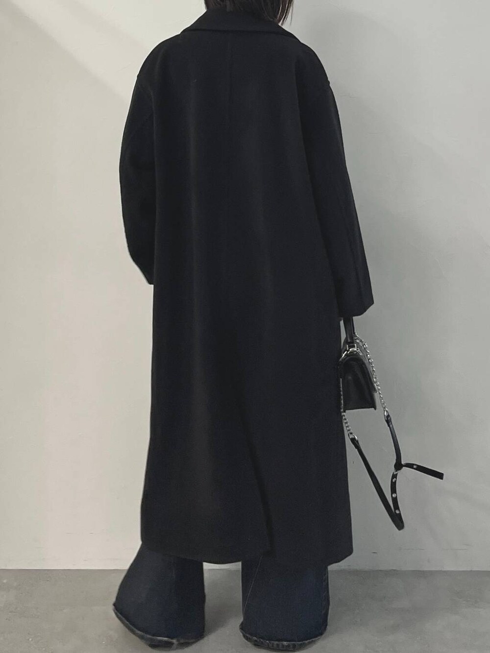 ブルー系のデニムパンツ、ブラック系のパンプス、ブラック系のチェスターコートを着用したレディースの秋コーディネートの8枚目の写真