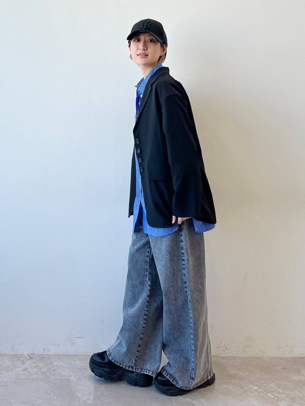 ブラック系のスニーカー、ブラック系のテーラードジャケット、ブラック系のデニムパンツを着用したレディースの春コーディネートの6枚目の写真