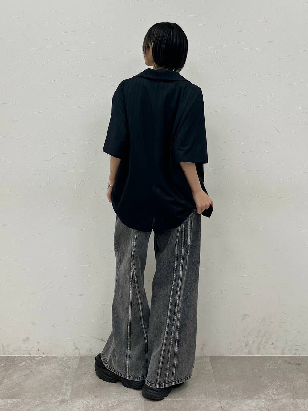 ブラック系のスニーカー、ブルー系のTシャツ/カットソー、ブラック系のデニムパンツを着用したレディースの春コーディネートの6枚目の写真