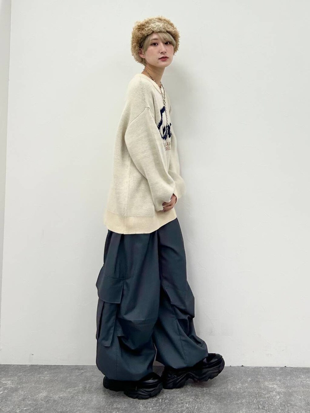 ブラック系のスニーカー、ホワイト系のニット/セーター、グレー系のカーゴパンツを着用したレディースの冬コーディネートの4枚目の写真