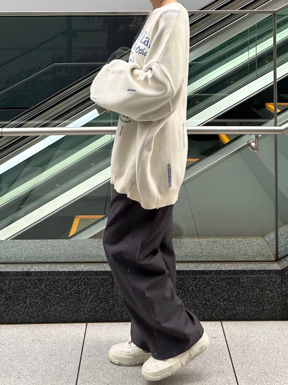 グレー系のスラックス、ホワイト系のニット/セーターを着用したレディースの冬コーディネートの4枚目の写真