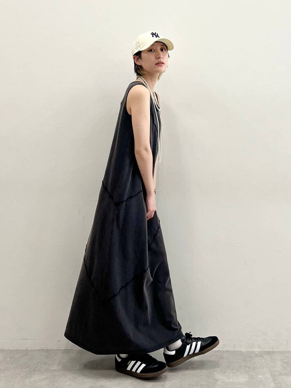 ブラック系のスニーカー、ブラック系のワンピース、ホワイト系のネックレスを着用したレディースの春コーディネートの6枚目の写真