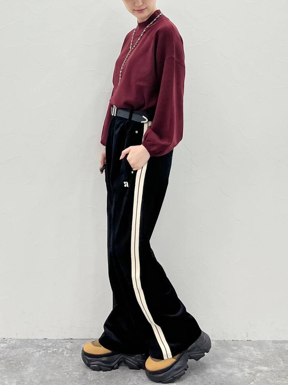 ブラウン系のブーツ、レッド系のニット/セーター、ブラック系のスウェットパンツを着用したレディースの秋コーディネートの4枚目の写真