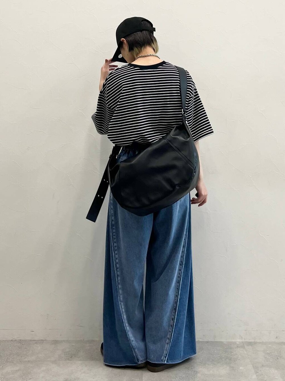 ブラック系のショルダーバッグ、ブラック系のスニーカー、ブルー系のデニムパンツを着用したレディースの春コーディネートの5枚目の写真