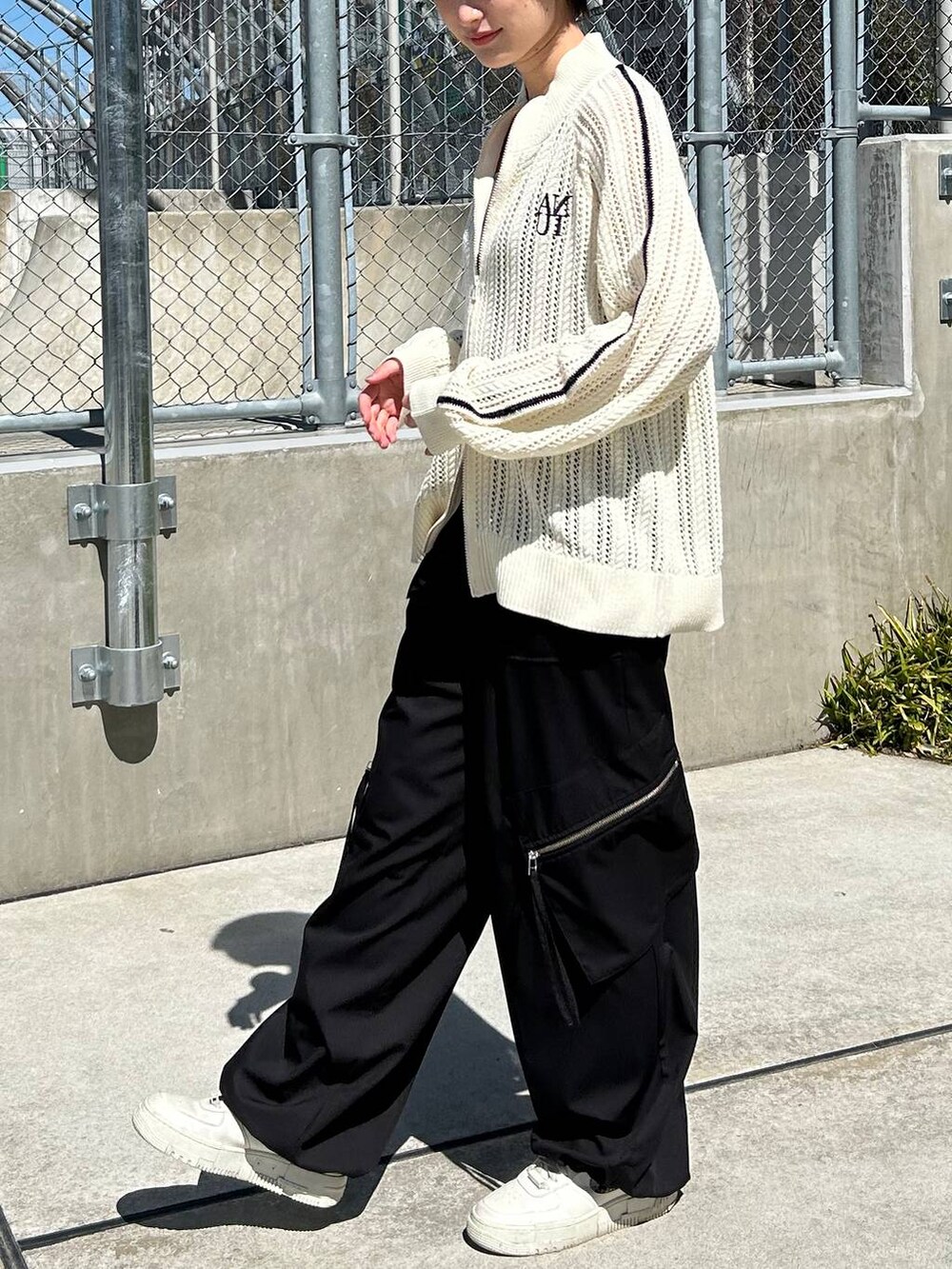 グレー系のタンクトップ、ホワイト系のカーディガン/ボレロ、ブラック系のスラックスを着用したレディースの春コーディネートの3枚目の写真