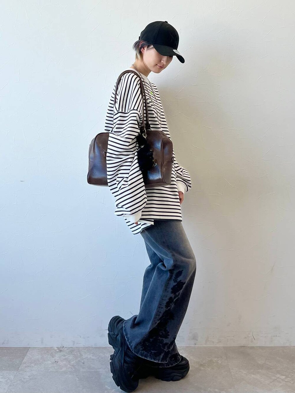 ブラック系のスニーカー、ブラウン系のボストンバッグ、ブラック系のデニムパンツを着用したレディースの春コーディネートの3枚目の写真