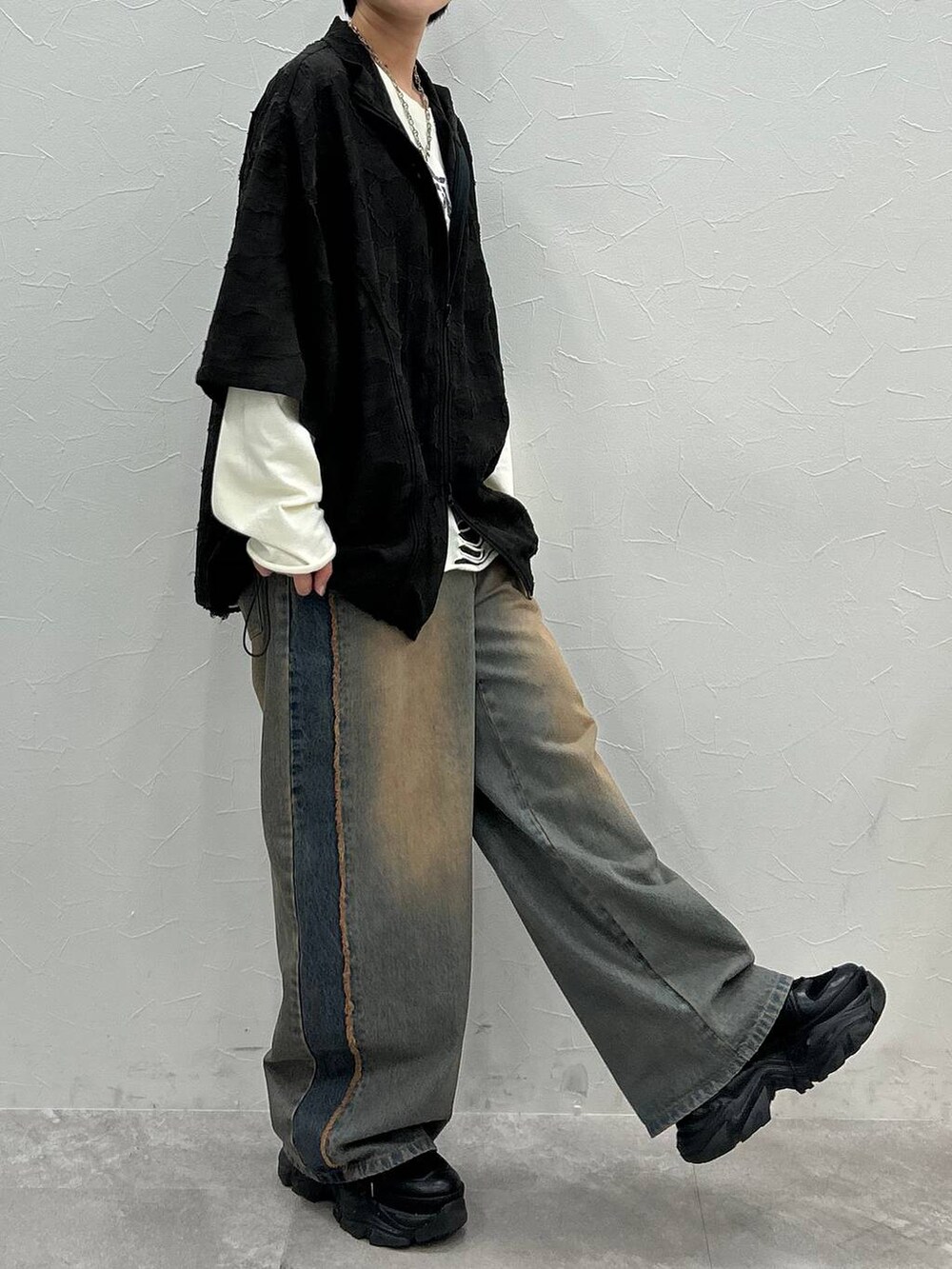 ブラック系のスニーカー、ホワイト系のTシャツ/カットソー、ブルー系のデニムパンツを着用したレディースの秋コーディネートの5枚目の写真