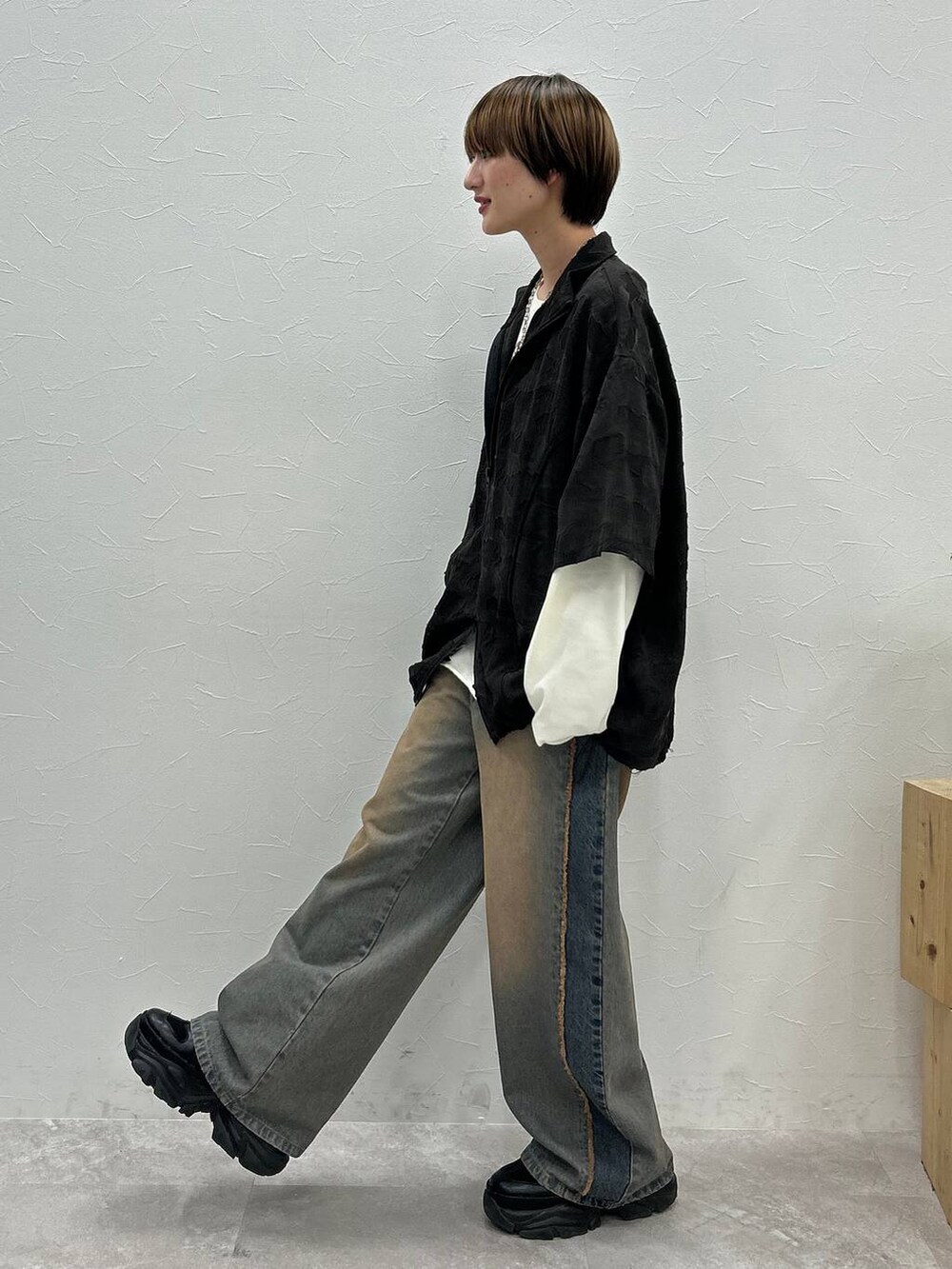 ブラック系のスニーカー、ホワイト系のTシャツ/カットソー、ブルー系のデニムパンツを着用したレディースの秋コーディネートの3枚目の写真