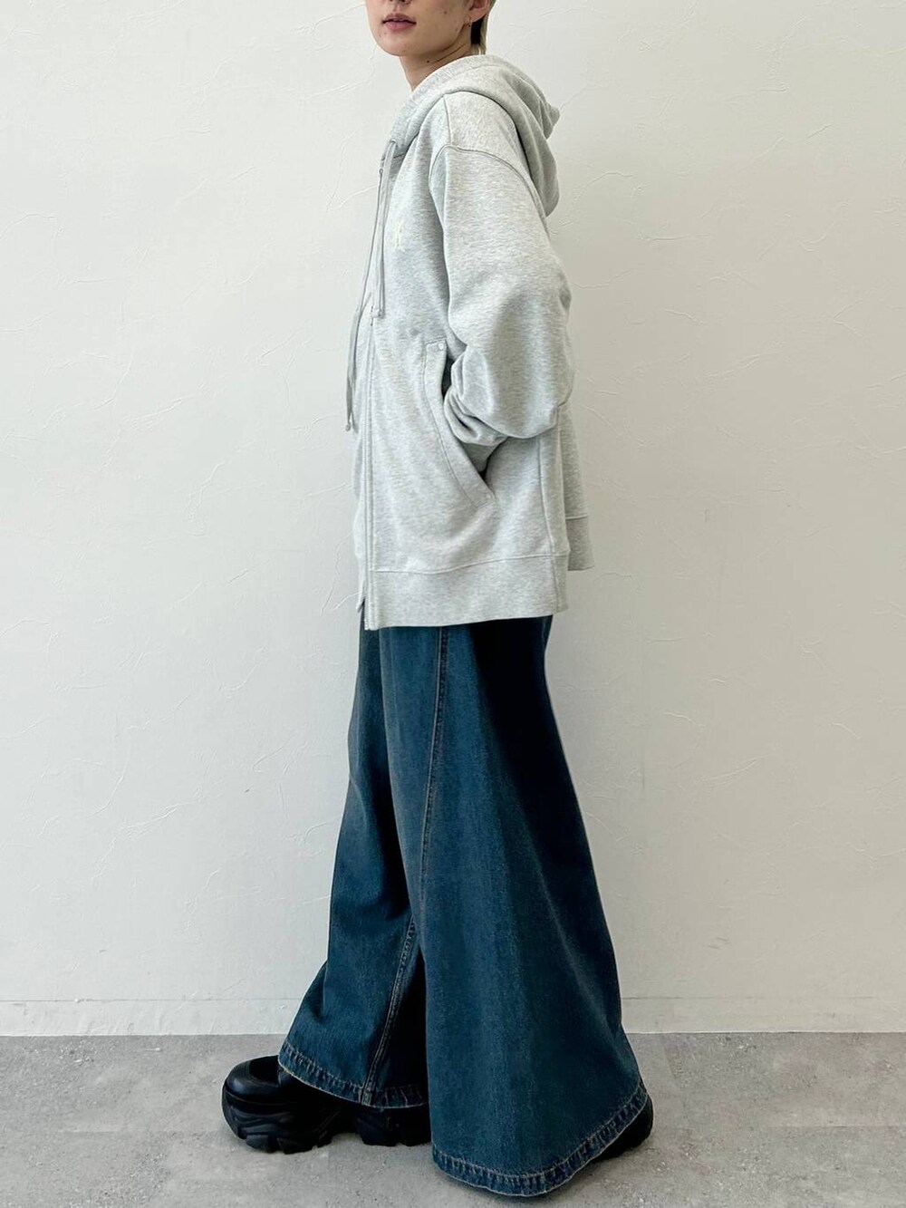 ブルー系のデニムパンツ、ブラック系のブーツ、グレー系のパーカーを着用したレディースの秋コーディネートの5枚目の写真