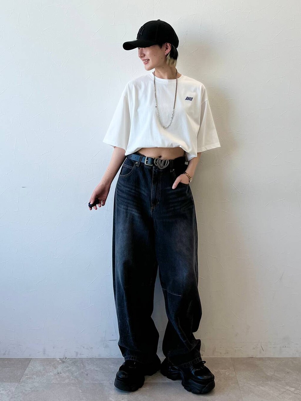 ブラック系のスニーカー、ブラック系のデニムパンツ、ホワイト系のTシャツ/カットソーを着用したレディースの春コーディネートの4枚目の写真