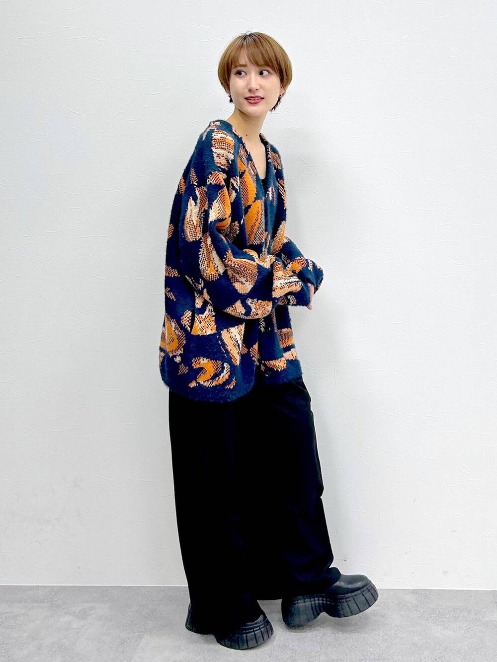 ブルー系のニット/セーター、ブラック系のブーツ、ブラック系のスラックスを着用したレディースの冬コーディネートの5枚目の写真