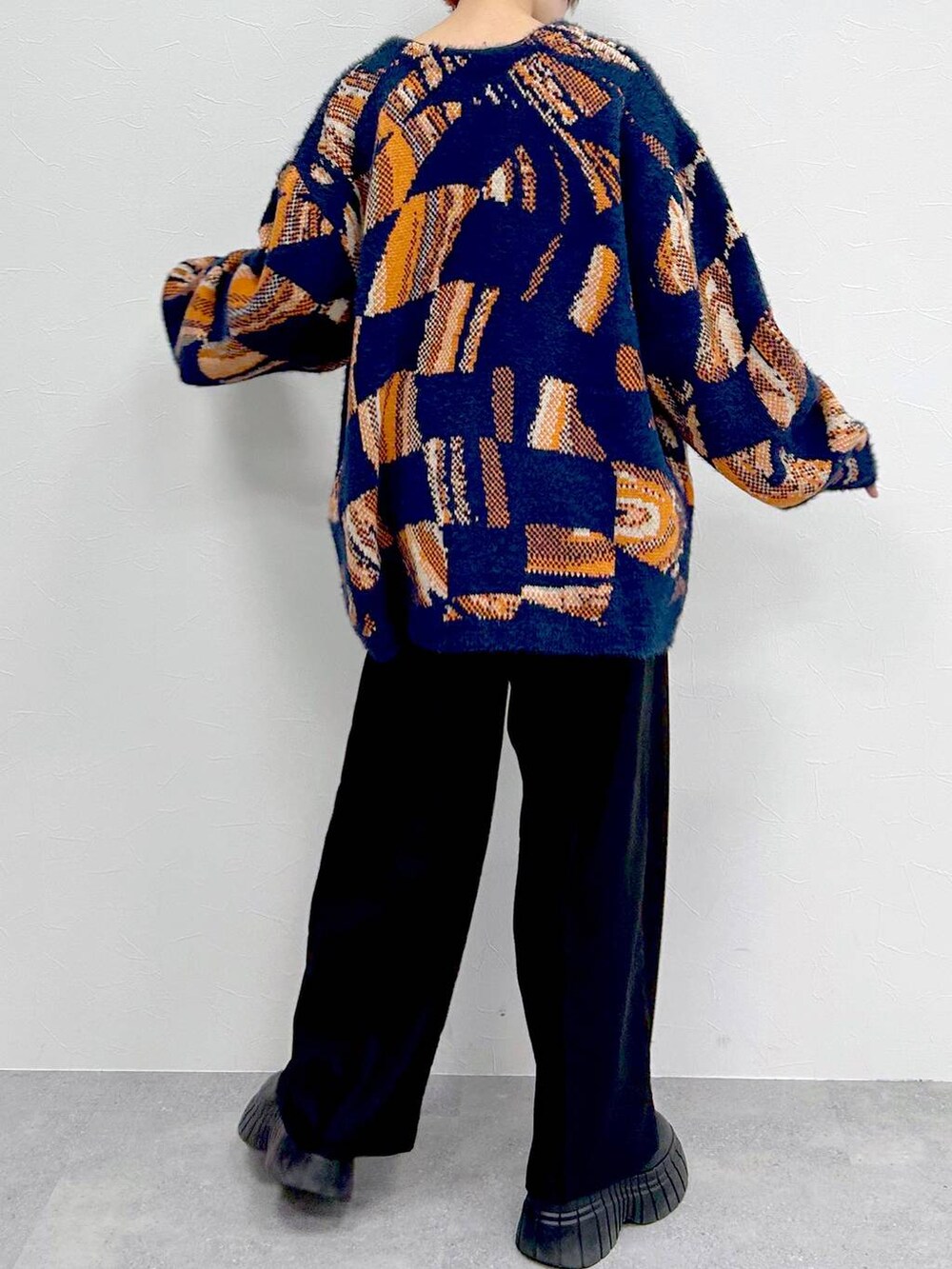 ブルー系のニット/セーター、ブラック系のブーツ、ブラック系のスラックスを着用したレディースの冬コーディネートの7枚目の写真