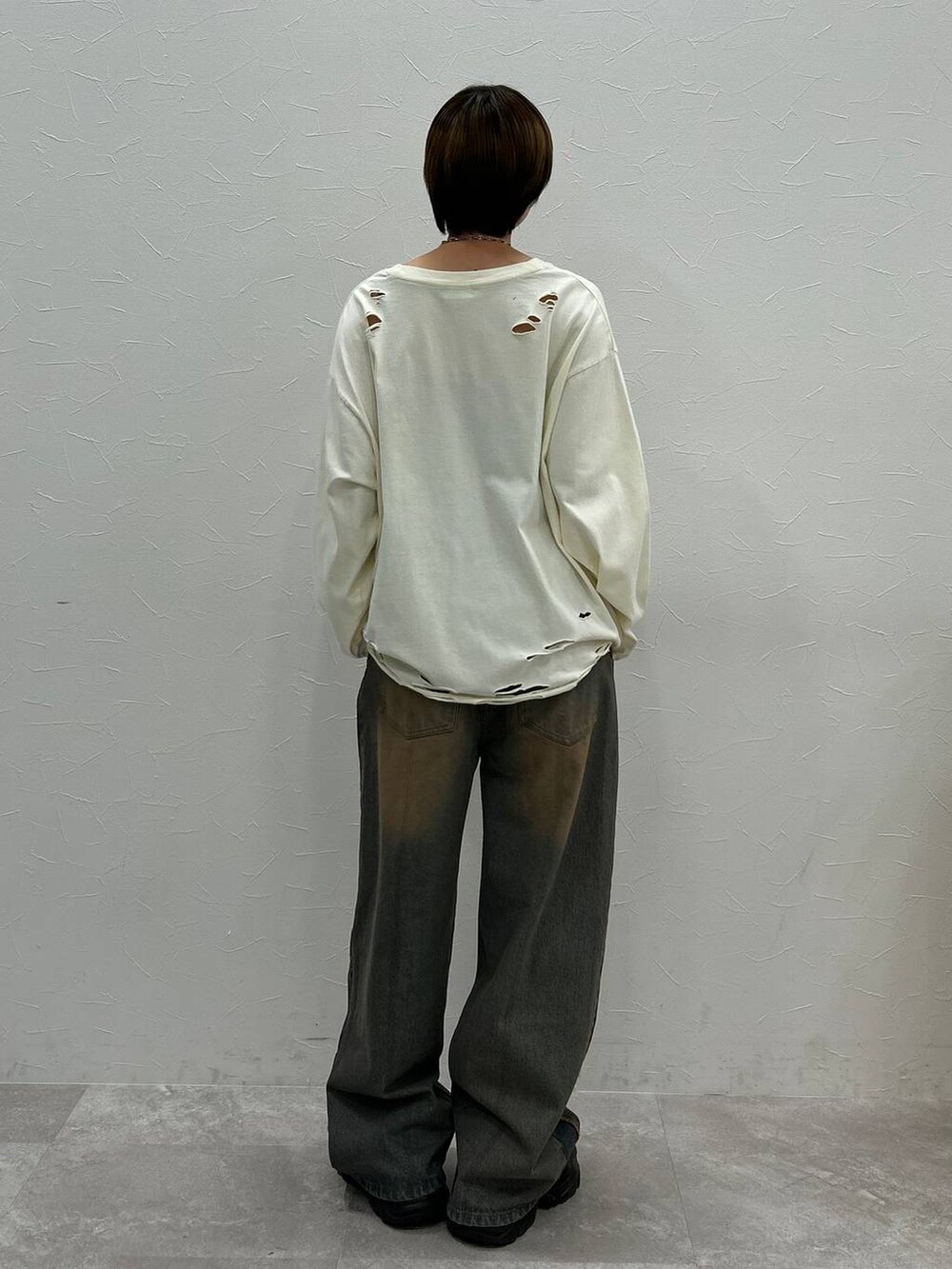 ブラック系のスニーカー、ホワイト系のTシャツ/カットソー、ブルー系のデニムパンツを着用したレディースの秋コーディネートの6枚目の写真