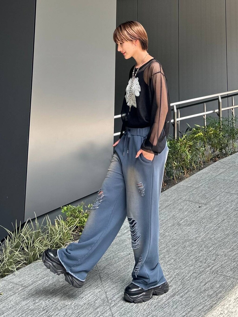 ブラック系のスニーカー、ブルー系のスウェットパンツ、ブラック系のニット/セーターを着用したレディースの夏コーディネートの3枚目の写真