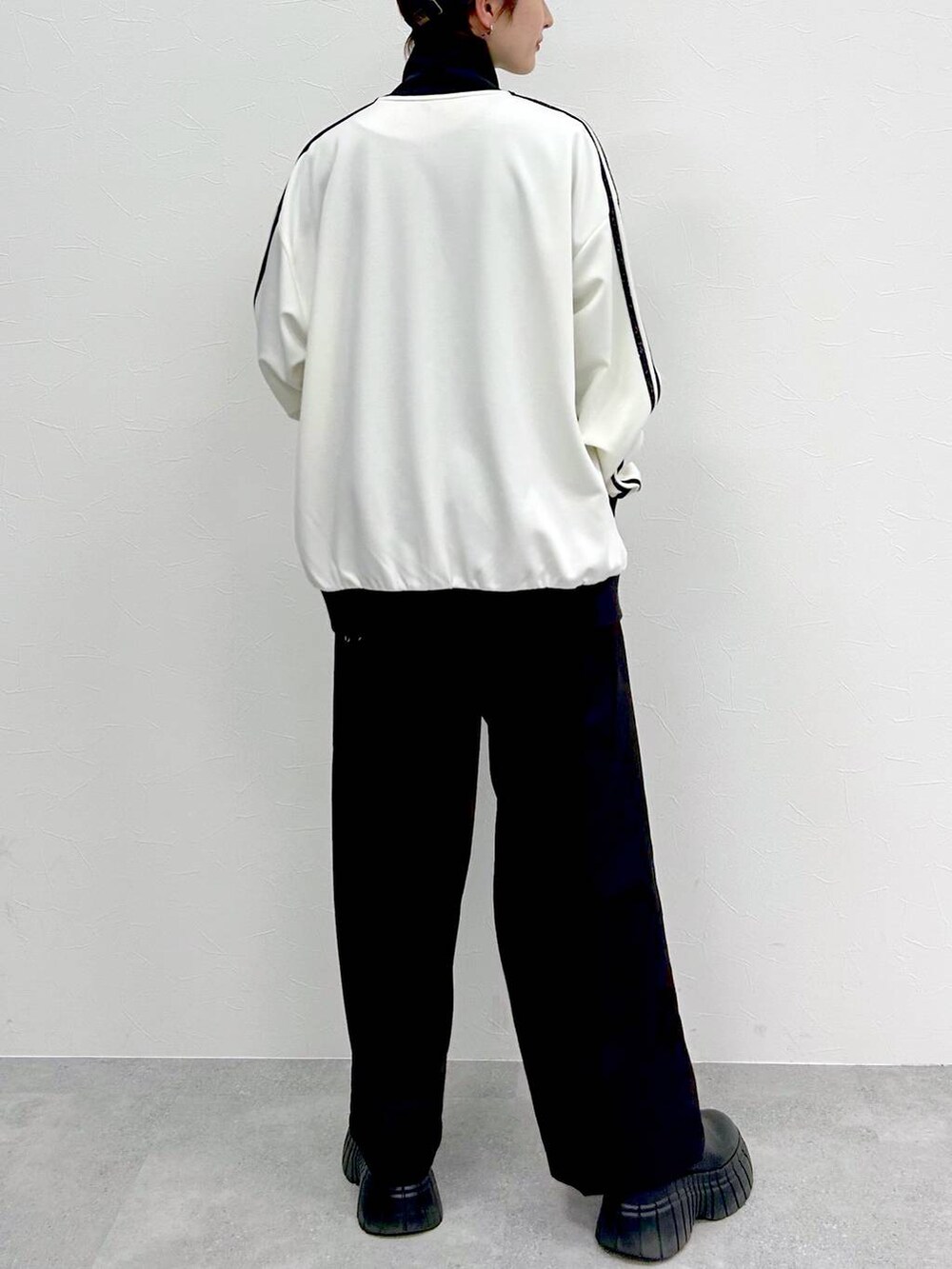 ホワイト系のその他アウター、ブラック系のスラックス、ブラック系のブーツを着用したレディースの春コーディネートの8枚目の写真