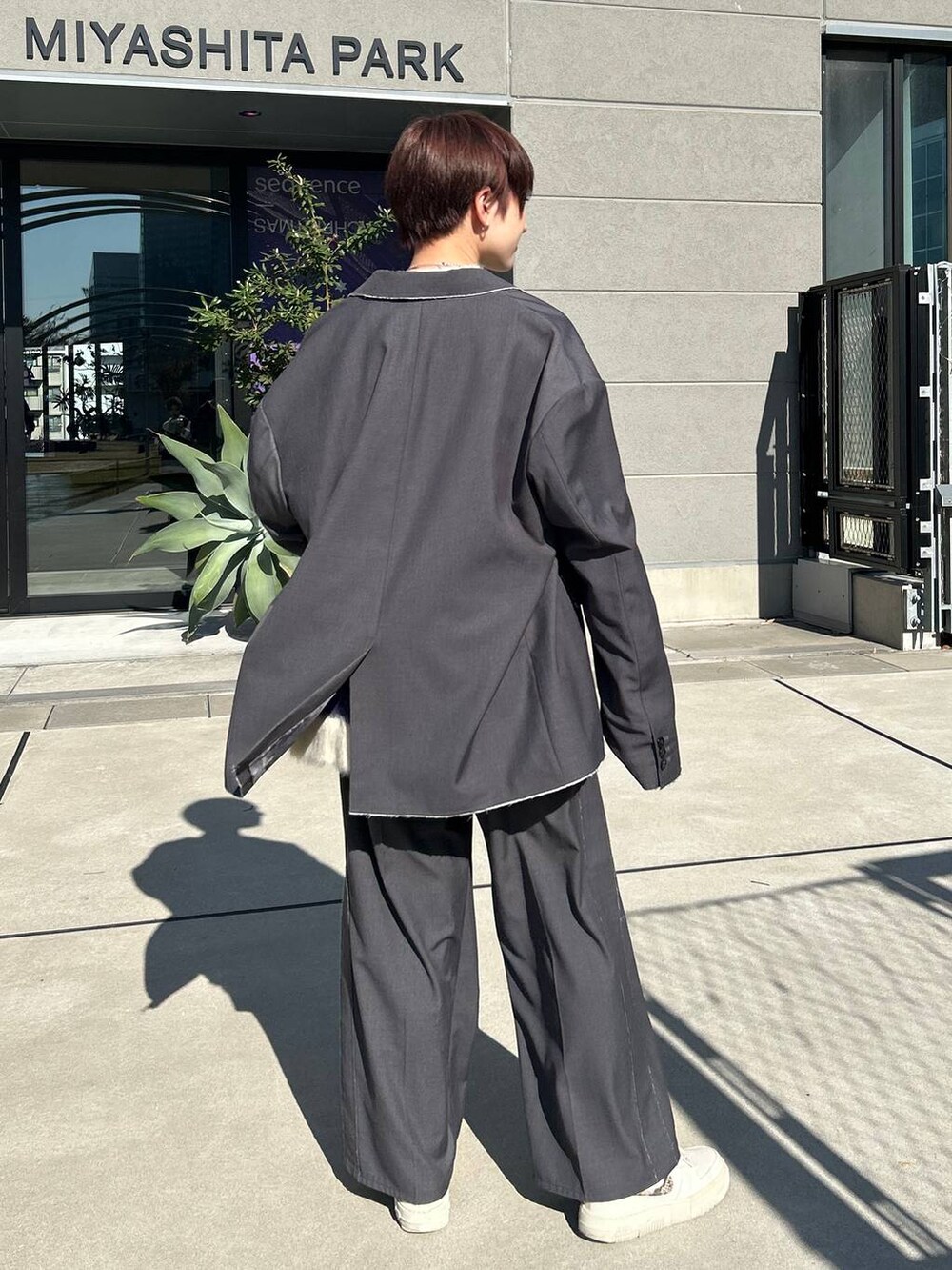 グレー系のスラックス、グレー系のテーラードジャケット、ブルー系のニット/セーターを着用したレディースの冬コーディネートの6枚目の写真