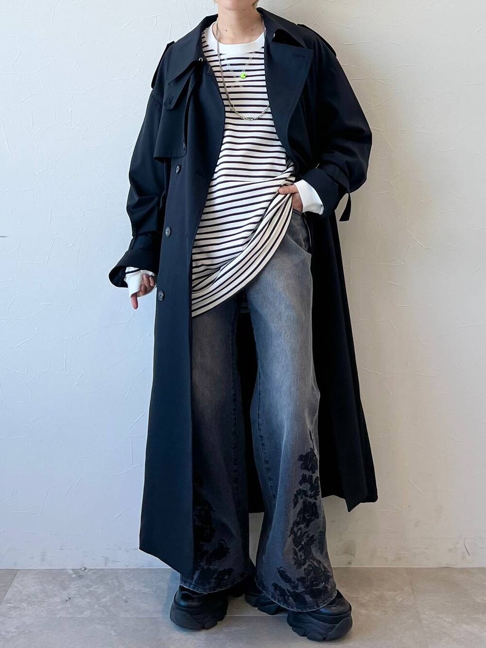 ブラック系のスニーカー、ブラック系のトレンチコート、ブラック系のデニムパンツを着用したレディースの春コーディネートの3枚目の写真