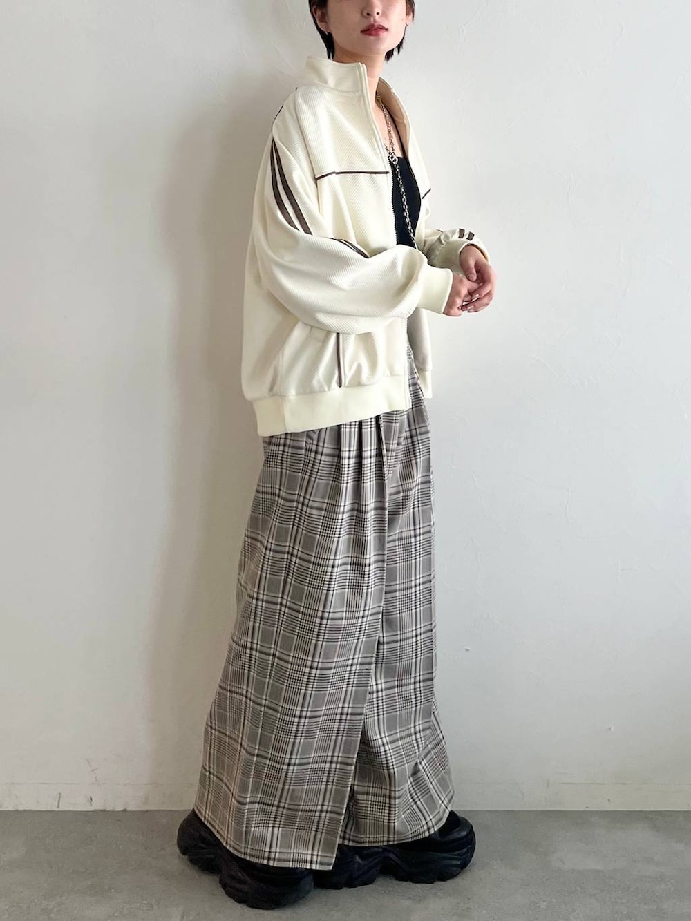 ブラック系のスニーカー、ベージュ系のスラックス、ホワイト系のジャージを着用したレディースの秋コーディネートの3枚目の写真