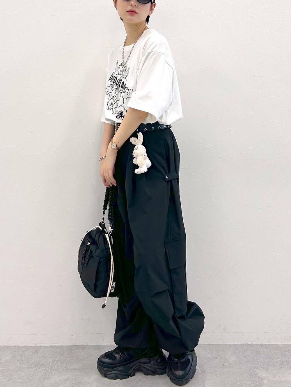 ブラック系のスニーカー、ホワイト系のTシャツ/カットソー、ブラック系のショルダーバッグを着用したレディースの夏コーディネートの5枚目の写真