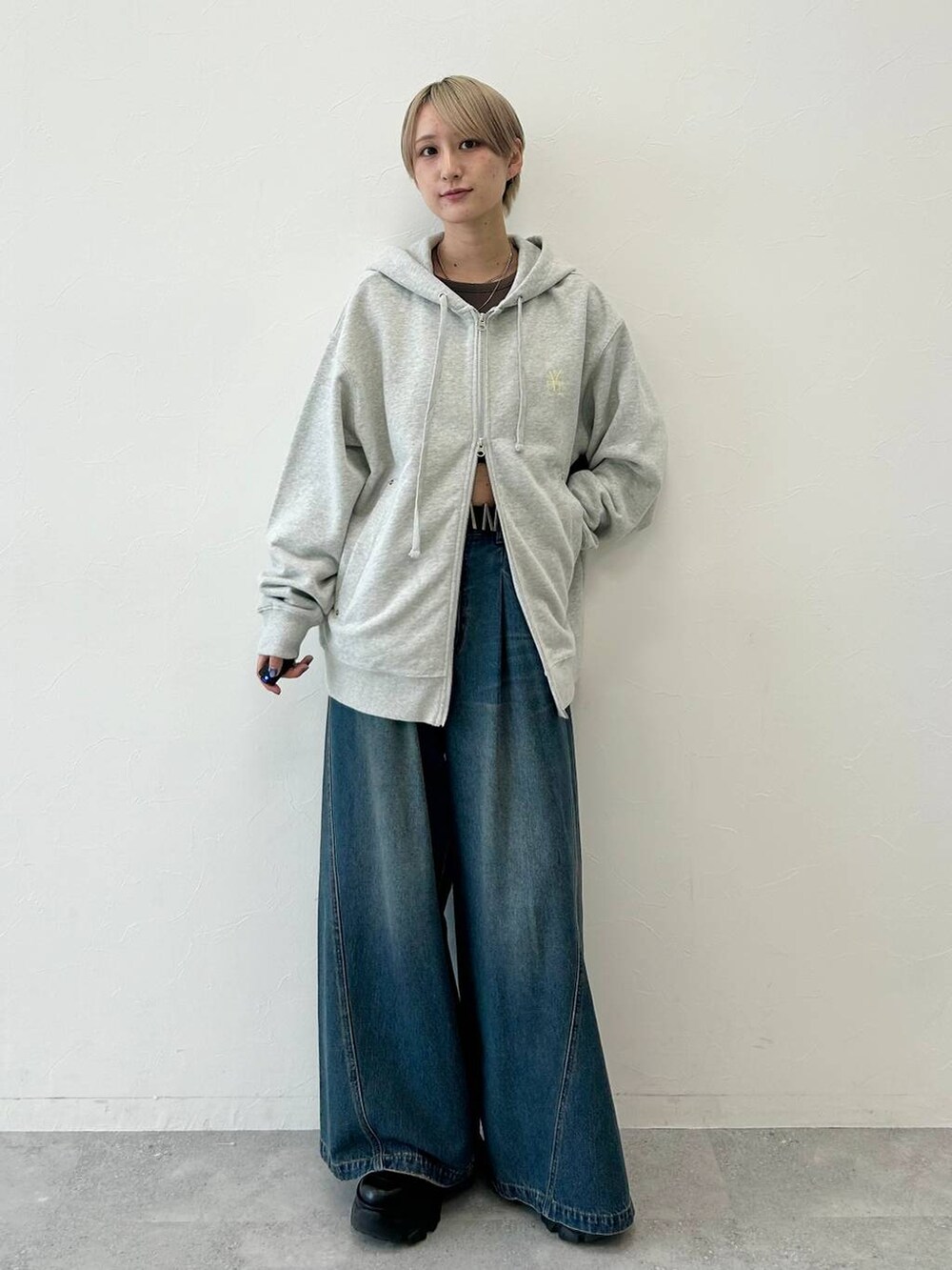 ブルー系のデニムパンツ、ブラック系のブーツ、グレー系のパーカーを着用したレディースの秋コーディネートの2枚目の写真