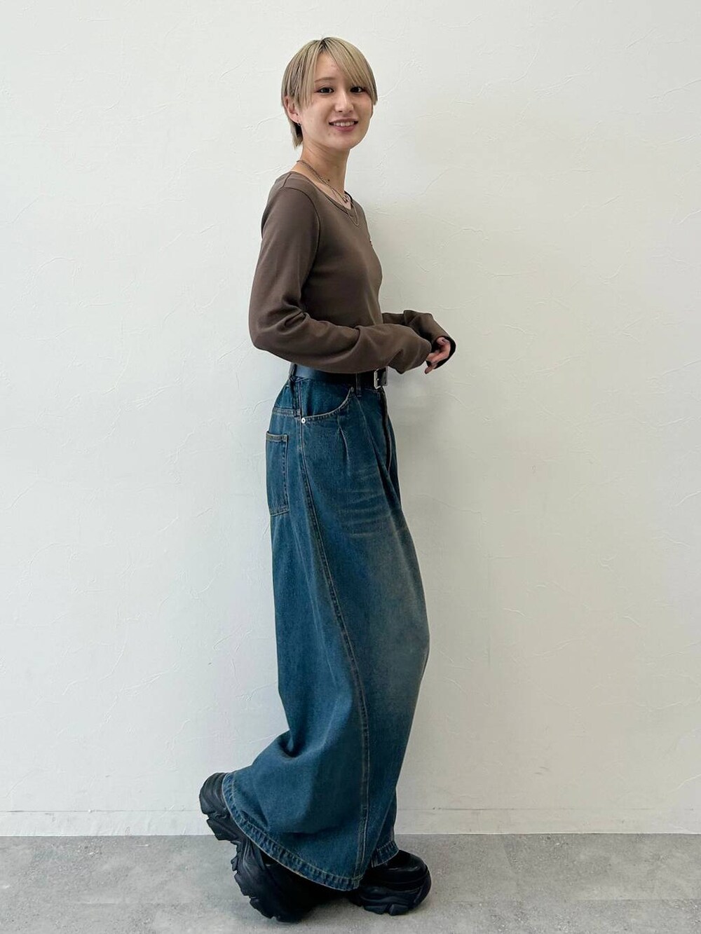 ブルー系のデニムパンツ、ブラック系のブーツ、ブラウン系のTシャツ/カットソーを着用したレディースの冬コーディネートの3枚目の写真