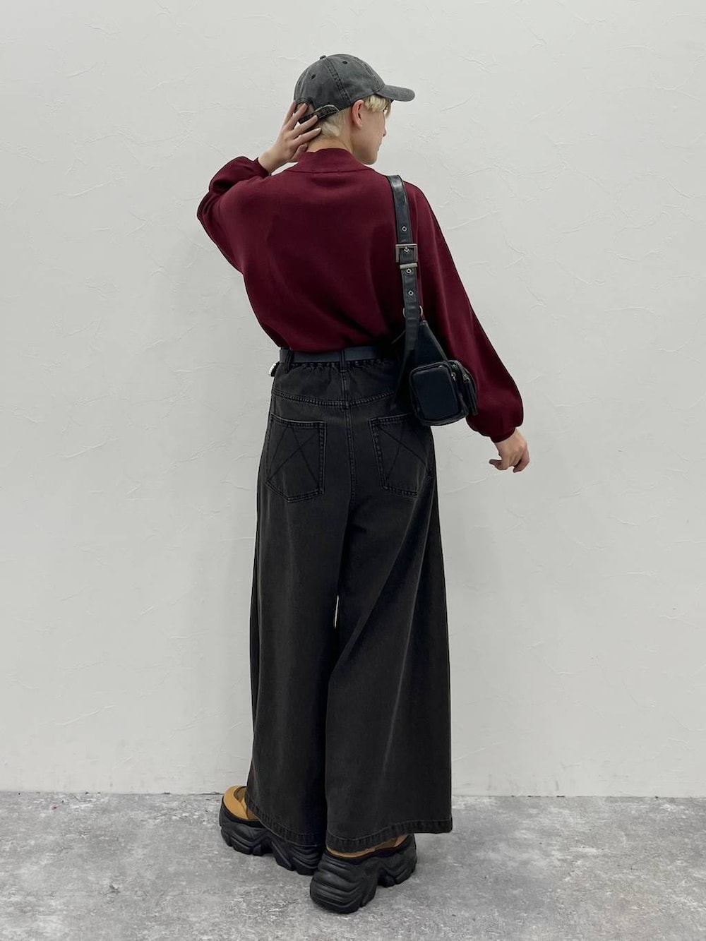 ブラック系のデニムパンツ、ブラウン系のブーツ、レッド系のニット/セーターを着用したレディースの秋コーディネートの6枚目の写真