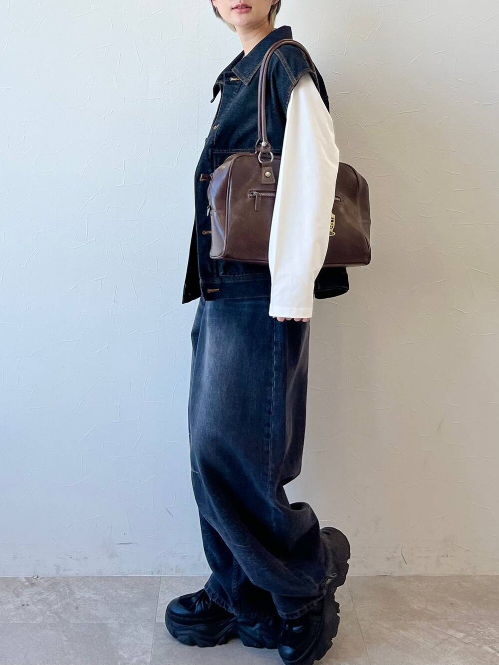 ブラック系のスニーカー、ブラック系のデニムパンツ、ブラウン系のボストンバッグを着用したレディースの春コーディネートの7枚目の写真