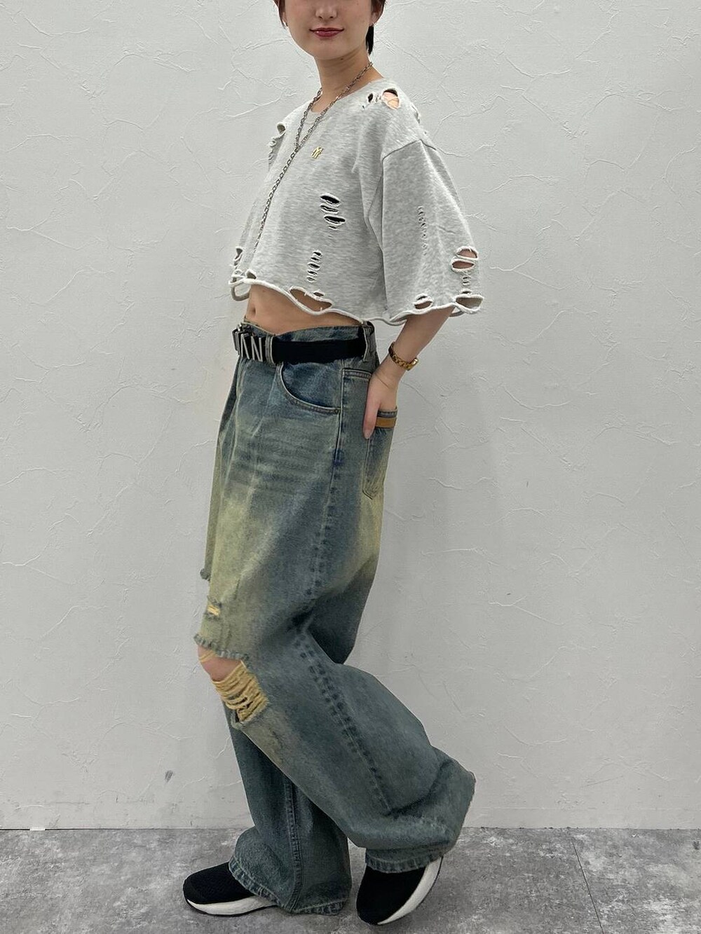 グレー系のTシャツ/カットソー、ブルー系のデニムパンツ、グリーン系のキャップを着用したレディースの秋コーディネートの4枚目の写真