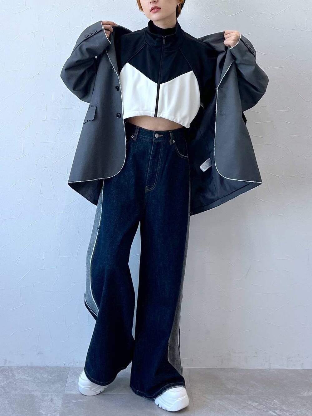 ブルー系のデニムパンツ、グレー系のテーラードジャケット、ブラック系のナイロンジャケットを着用したレディースの秋コーディネートの3枚目の写真