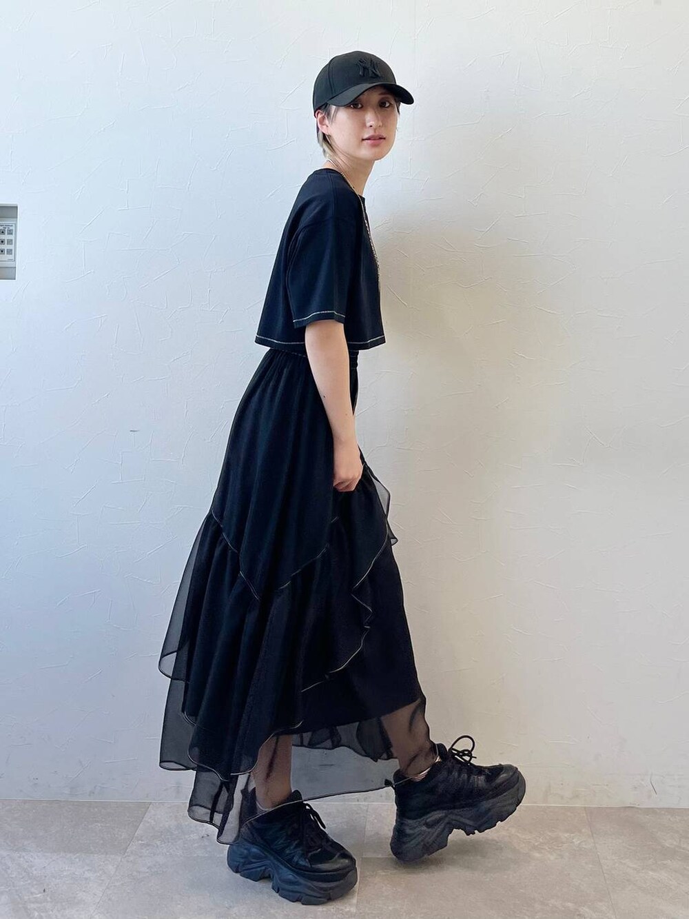 ブラック系のスニーカー、ブラック系のスカート、ブラック系のTシャツ/カットソーを着用したレディースの春コーディネートの3枚目の写真