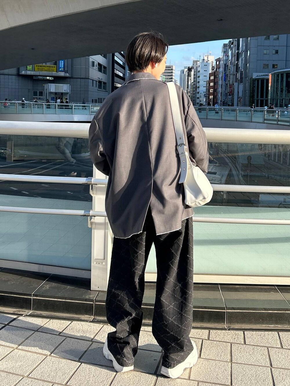 グレー系のテーラードジャケット、ブラック系のニット/セーター、ブラック系のデニムパンツを着用したレディースの冬コーディネートの6枚目の写真