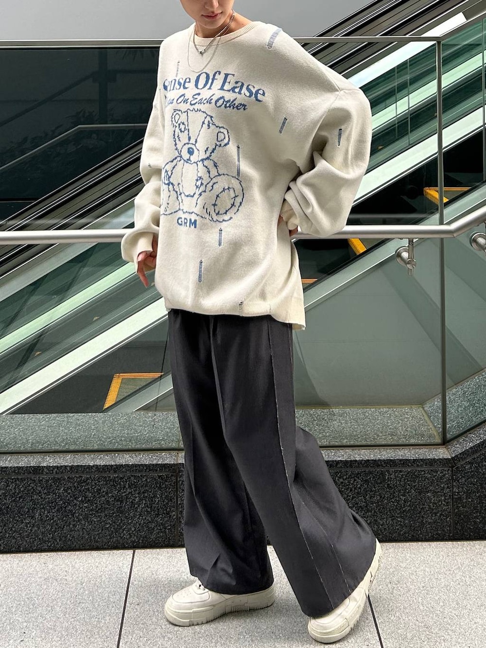 グレー系のスラックス、ホワイト系のニット/セーターを着用したレディースの冬コーディネートの3枚目の写真