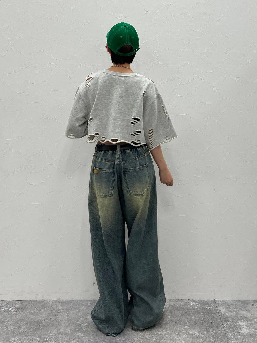 グレー系のTシャツ/カットソー、ブルー系のデニムパンツ、グリーン系のキャップを着用したレディースの秋コーディネートの7枚目の写真