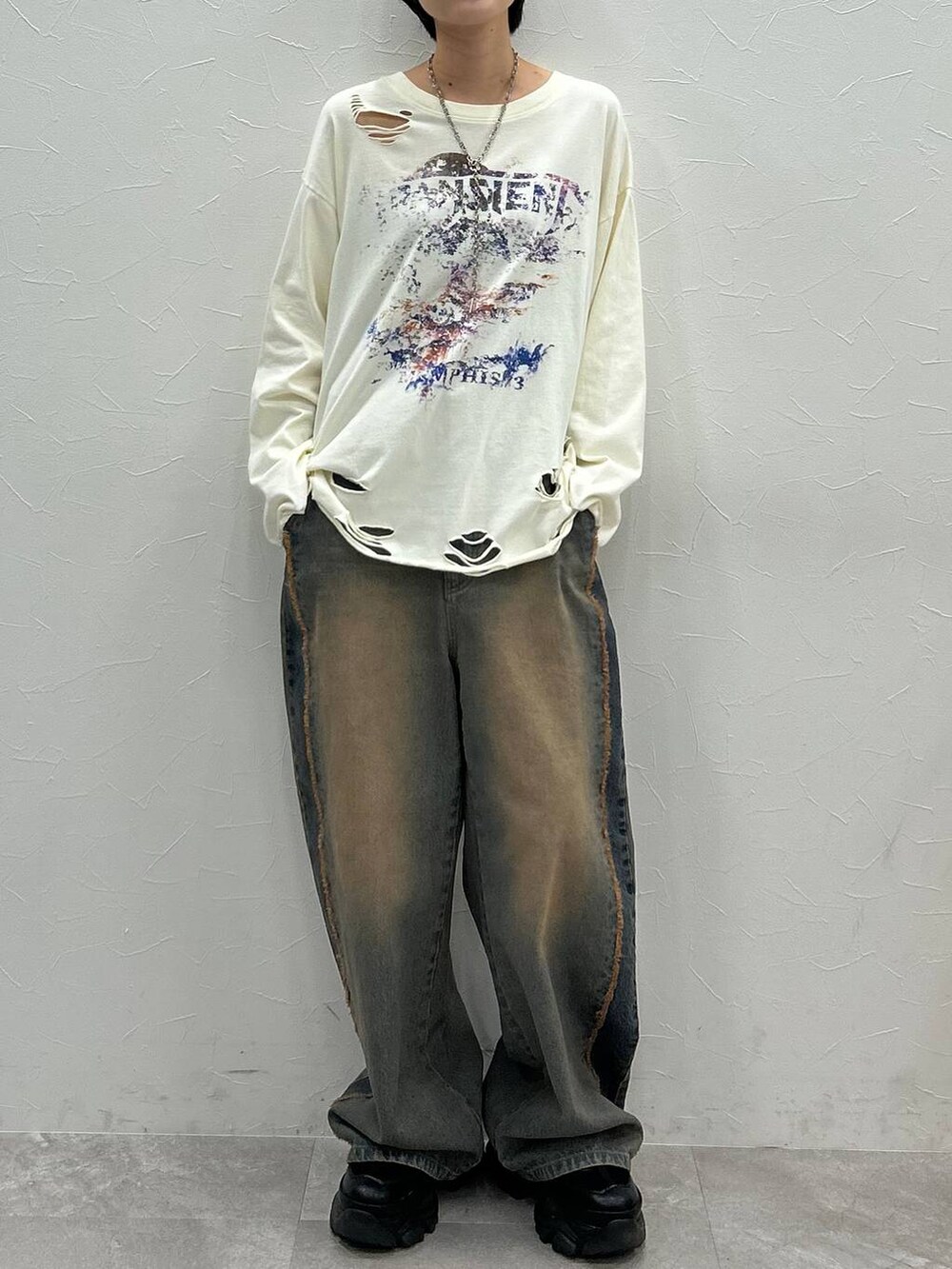 ブラック系のスニーカー、ホワイト系のTシャツ/カットソー、ブルー系のデニムパンツを着用したレディースの秋コーディネートの2枚目の写真