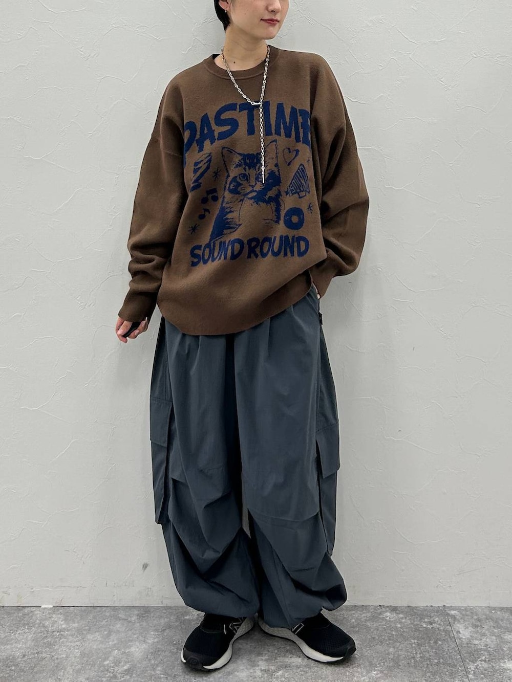 グレー系のカーゴパンツ、ブラウン系のニット/セーター、ブラック系のニットキャップ/ビーニーを着用したレディースの秋コーディネートの2枚目の写真