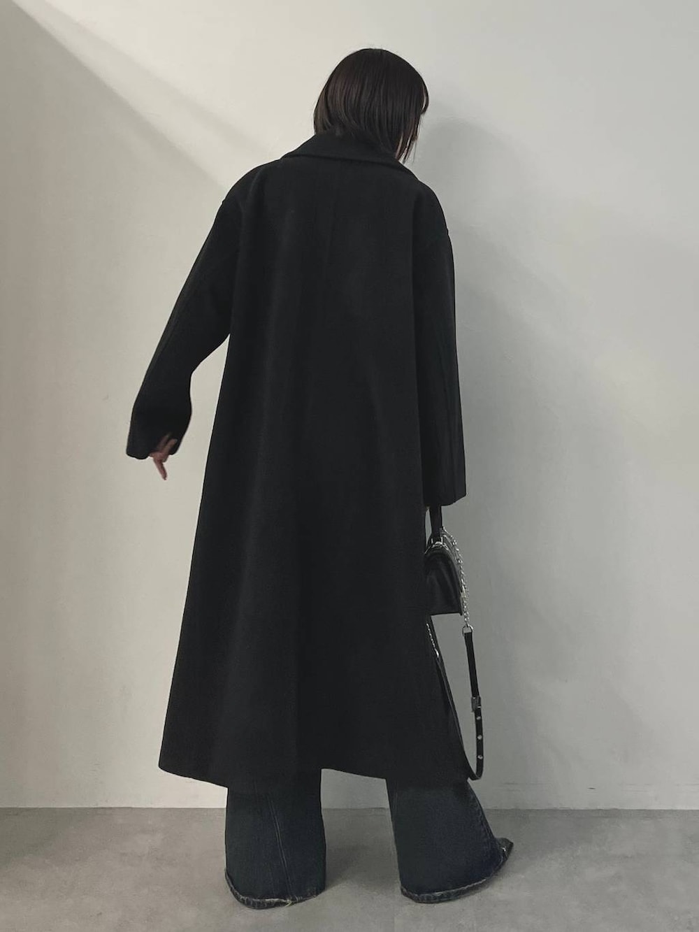 ブルー系のデニムパンツ、ブラック系のパンプス、ブラック系のチェスターコートを着用したレディースの秋コーディネートの7枚目の写真