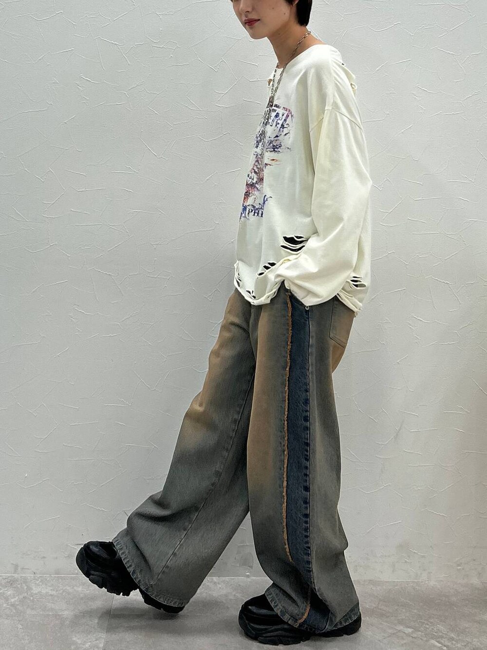 ブラック系のスニーカー、ホワイト系のTシャツ/カットソー、ブルー系のデニムパンツを着用したレディースの秋コーディネートの5枚目の写真