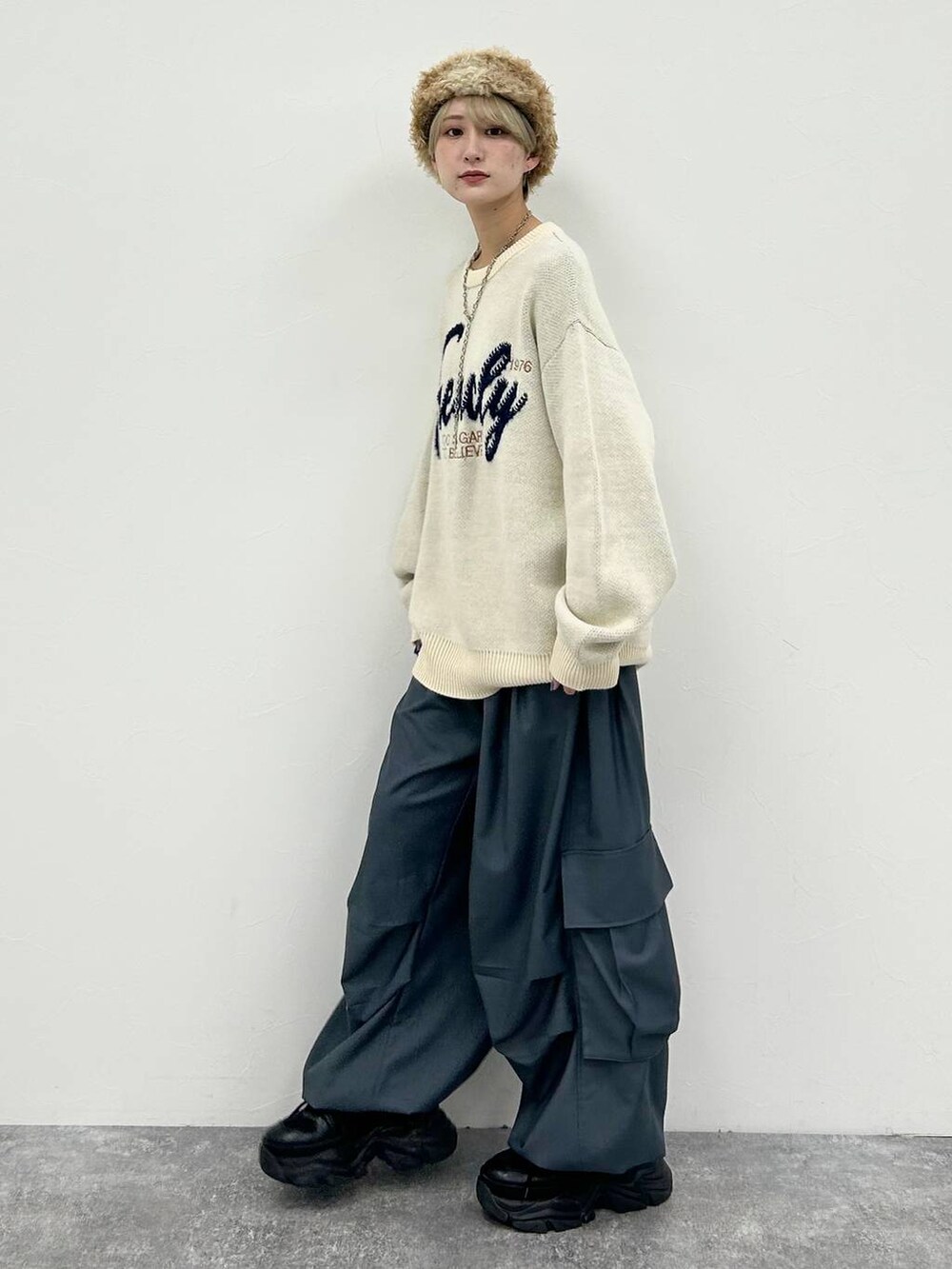 ブラック系のスニーカー、ホワイト系のニット/セーター、グレー系のカーゴパンツを着用したレディースの冬コーディネートの2枚目の写真